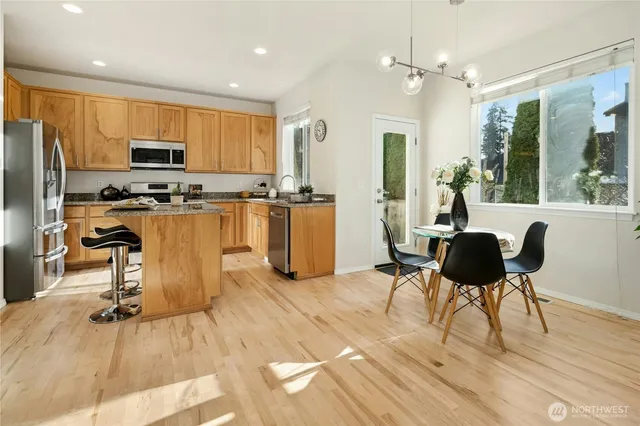 a living room with stainless steel appliances furniture a rug kitchen view and a large window