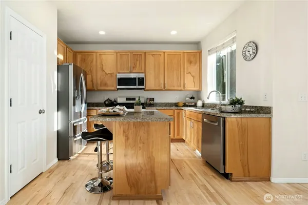 a kitchen with kitchen island granite countertop a stove top oven a sink and a granite counter top