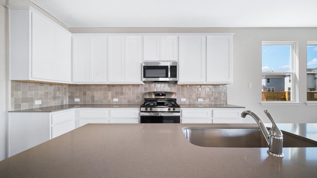 208 Stein Road Georgetown, TX 78626 - Photo 15 of 30 Kitchen with stainless steel appliances, white cabinetry, backsplash, and dark countertops