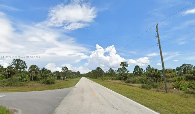 a view of a fountain in front of a big yard with plants