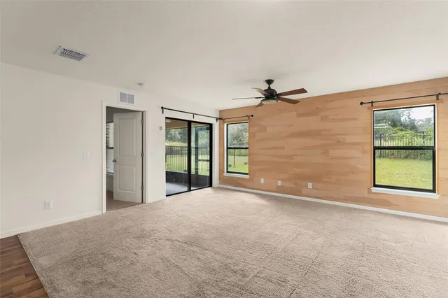 a view of a big room with windows and chandelier fan