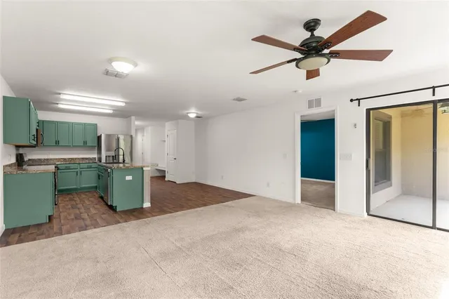 a view of a livingroom with a ceiling fan and kitchen view