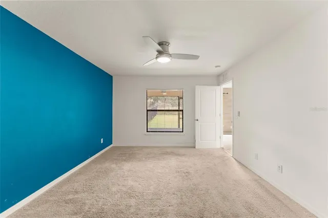 an empty room with windows and ceiling fan