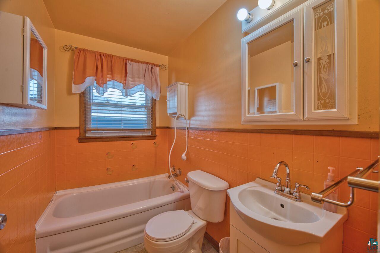 5316 Highway 110 Aurora, MN 55705 - Photo 15 of 35 Full bath featuring vanity, shower / bathtub combination, a wainscoted wall, and tile walls