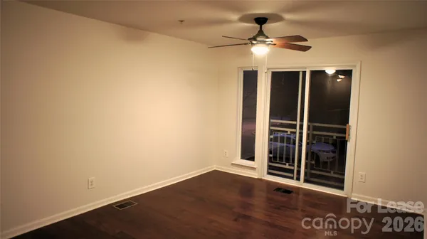 an empty room with wooden floor closet fan and windows