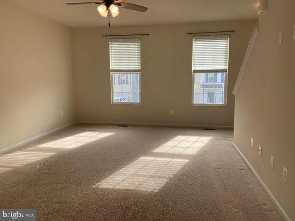 an empty room with a chandelier fan and windows