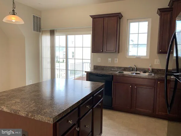 a kitchen with kitchen island granite countertop a sink cabinets and window