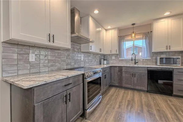 a kitchen with stainless steel appliances granite countertop a refrigerator a sink dishwasher a stove and a refrigerator