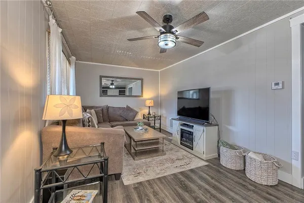 a living room with furniture a large window and wooden floor