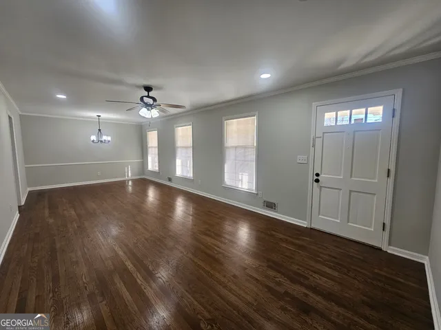 a view of an empty room with wooden floor and a window