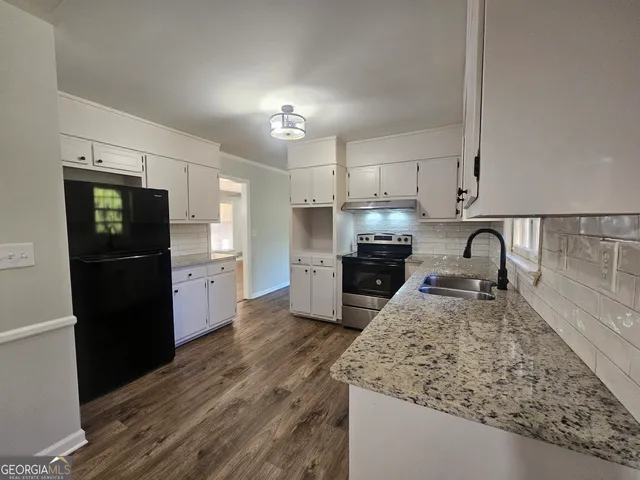 a kitchen with granite countertop a refrigerator and a sink