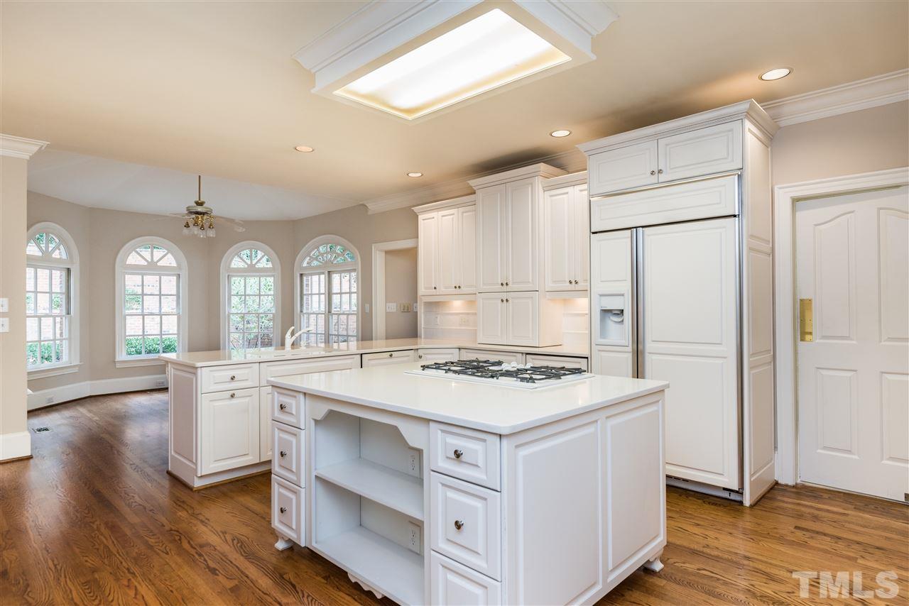 3103 Landor Road Raleigh, NC 27609 - Photo 9 of 25 a kitchen with a stove a sink a refrigerator and white cabinets with wooden floor