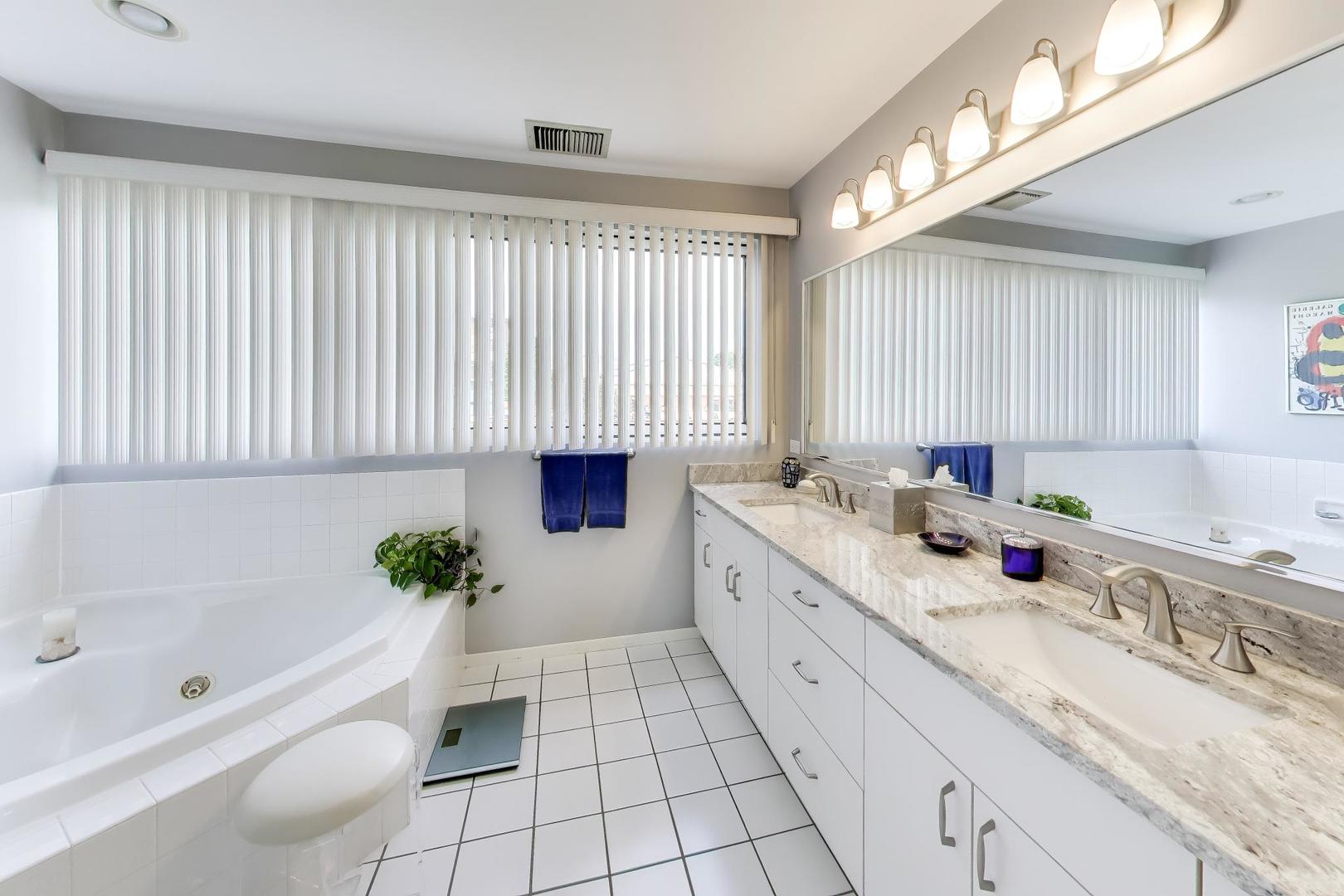 495 Milford Road Deerfield, IL 60015 - Photo 17 of 33 a spacious bathroom with a granite countertop tub a double vanity sink and a large mirror