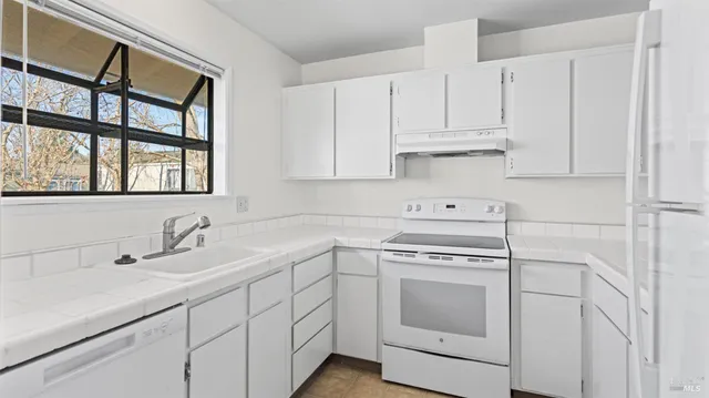 a kitchen with white cabinets and a stove with a sink