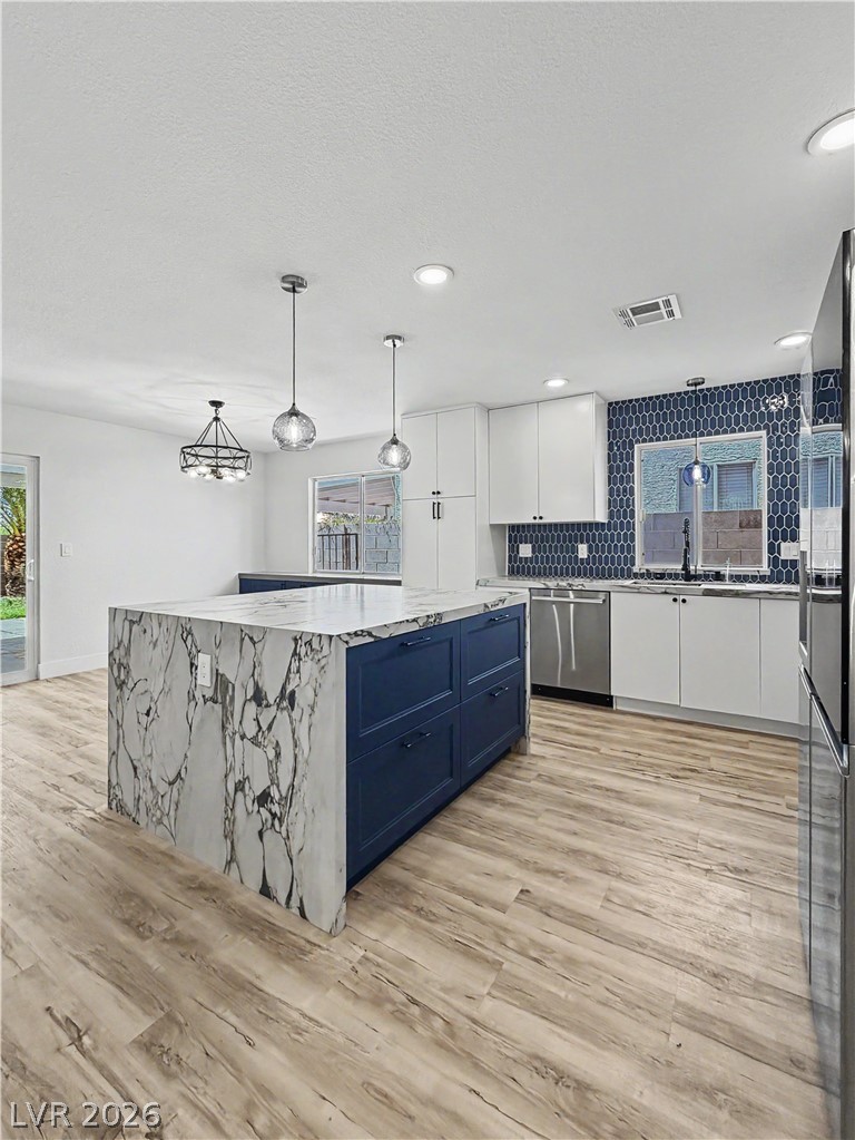 8977 Paige Rene Court Las Vegas, NV 89117 - Photo 7 of 31 A well-appointed culinary space featuring a waterfall-edge island, bright cabinetry, and stylish backsplash.