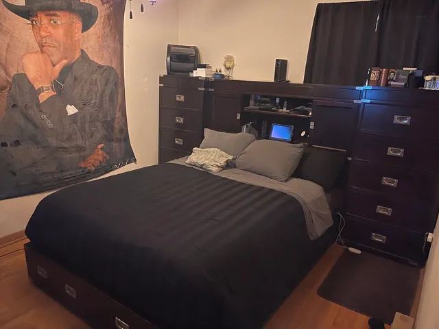 a bedroom with a bed and dresser with wall