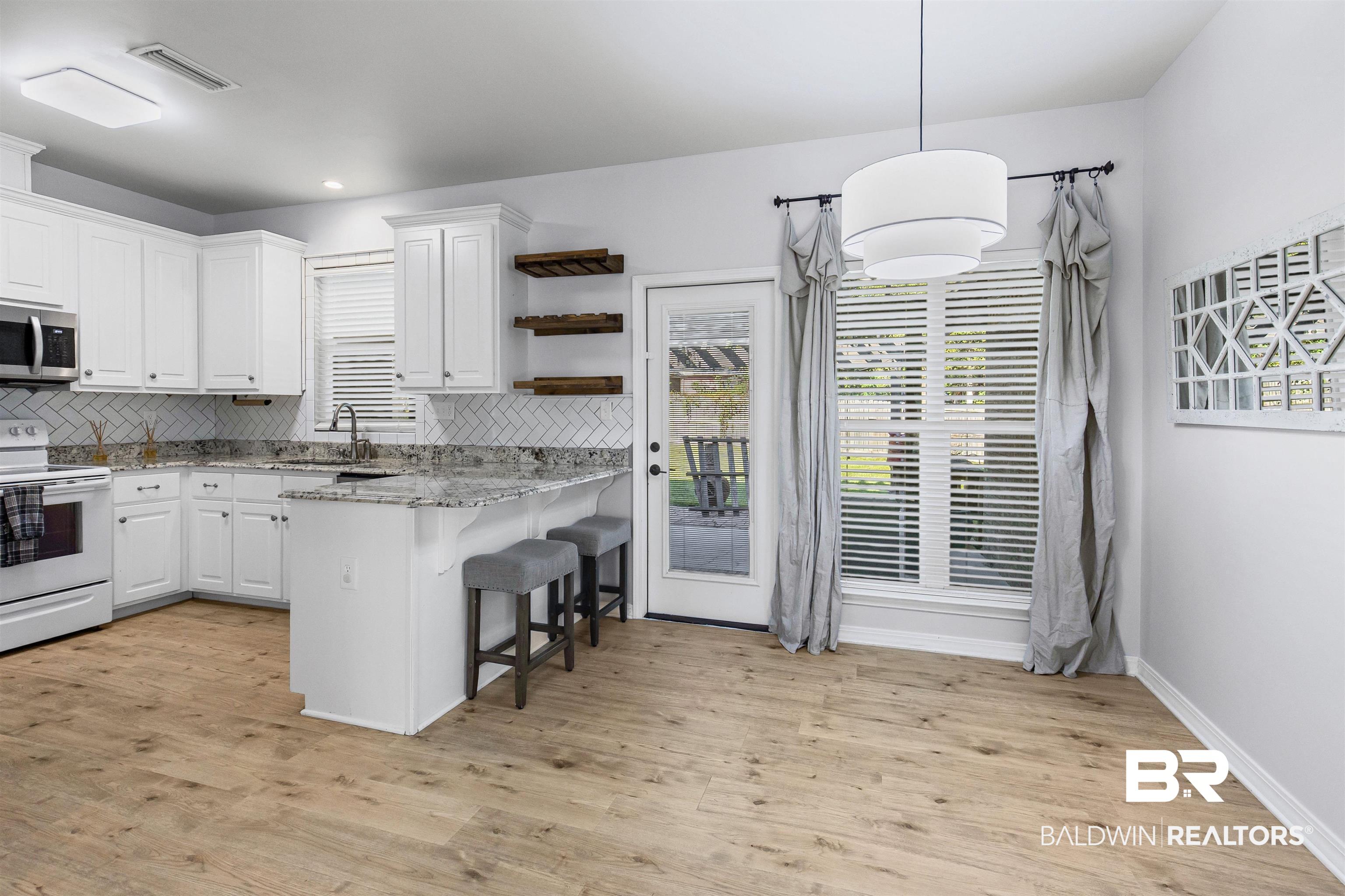 30851 Joseph Drive Spanish Fort, AL 36527 - Photo 5 of 22 Kitchen featuring white electric stove, tasteful backsplash, open shelves, decorative light fixtures, and light stone counters