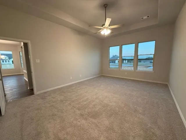 an empty room with chandelier fan and windows