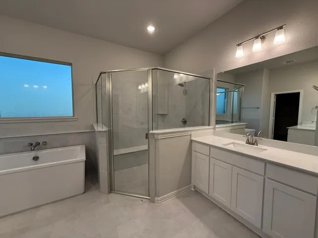 a bathroom with a double vanity sink mirror and bathtub