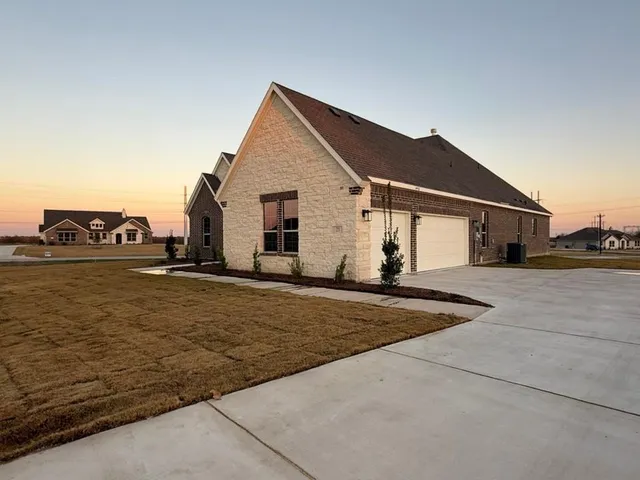a view of a white house next to a yard and road