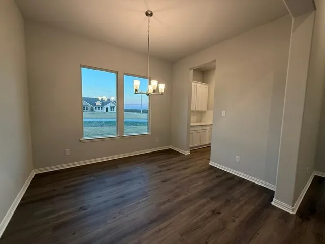 an empty room with wooden floor cabinet and windows