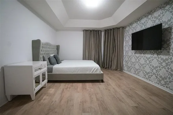 a spacious bedroom with a bed and a flat screen tv