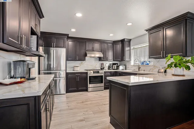 a kitchen with stainless steel appliances granite countertop a sink a stove and a refrigerator