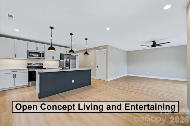 a kitchen with kitchen island granite countertop a refrigerator a sink a stove a microwave and wooden cabinets