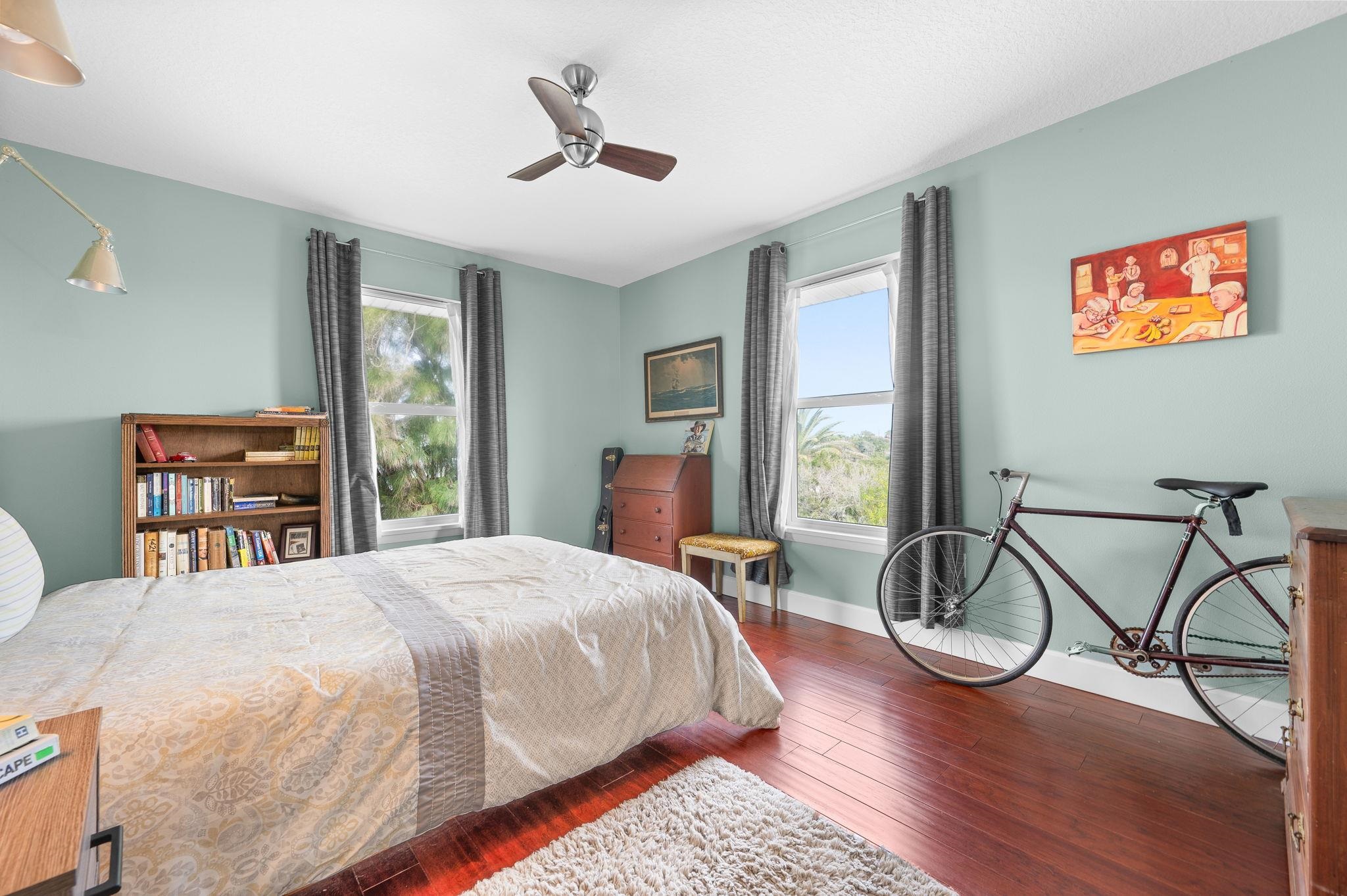 8950 Gene Johnson Road St. Augustine, FL 32080 - Photo 12 of 31 a bedroom with a bed a desk and chair with wooden floor