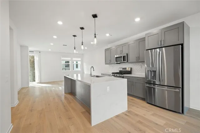 a large kitchen with stainless steel appliances kitchen island a large counter top and wooden floors
