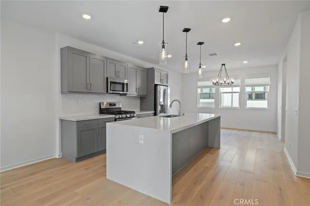 a large white kitchen with kitchen island a sink white cabinets and stainless steel appliances