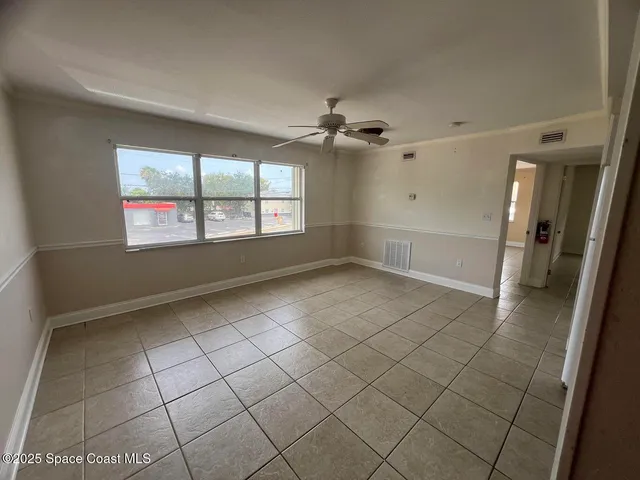 an empty room with windows and fan