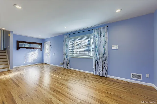 a view of an empty room with window and wooden floor