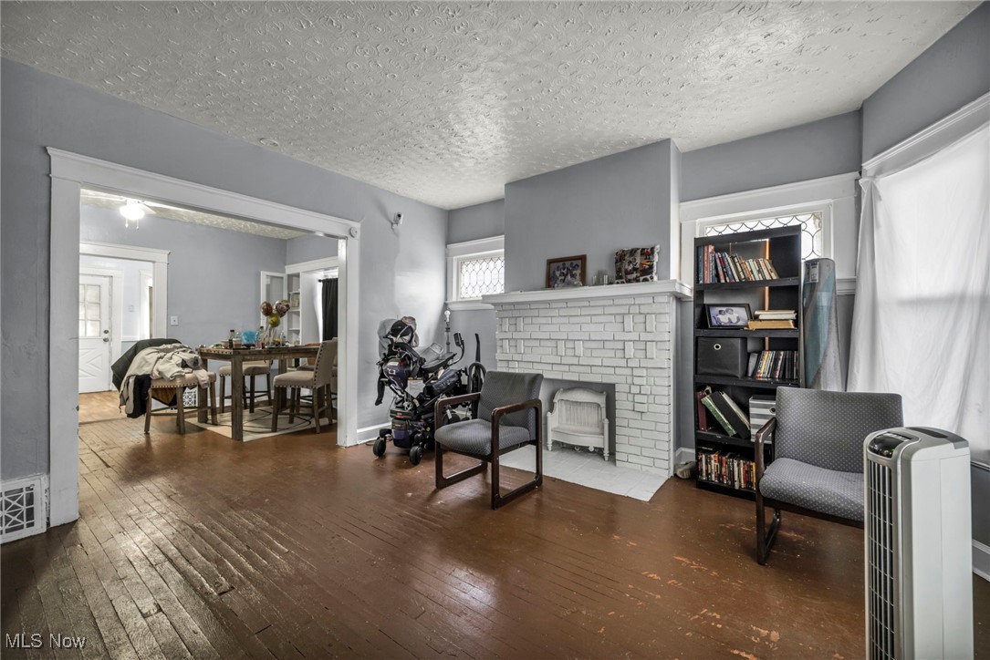 738 Eddy Road Cleveland, OH 44108 - Photo 11 of 33 Living area with dark wood finished floors, a brick fireplace, and a textured ceiling