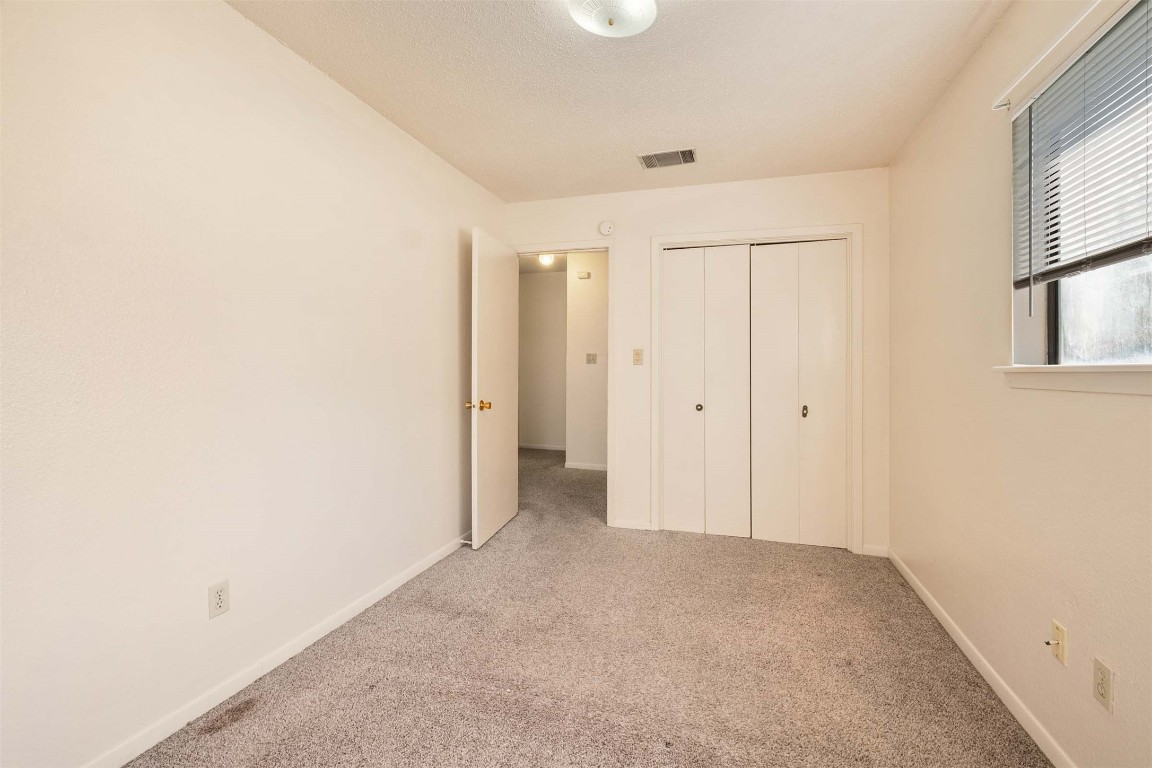 200 Concho Street, Unit B Lockhart, TX 78644 - Photo 13 of 13 Unfurnished bedroom featuring carpet flooring, a closet, and a textured ceiling