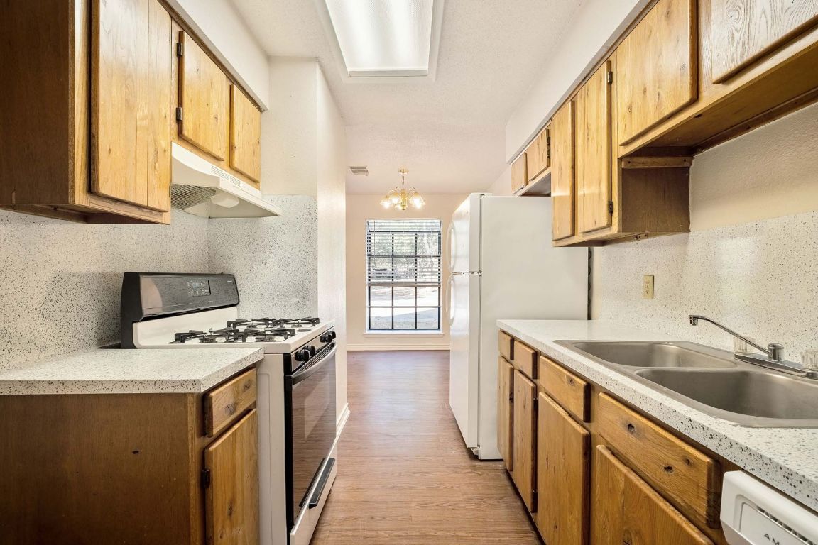 200 Concho Street, Unit B Lockhart, TX 78644 - Photo 5 of 13 Kitchen with white appliances, a chandelier, backsplash, and light countertops