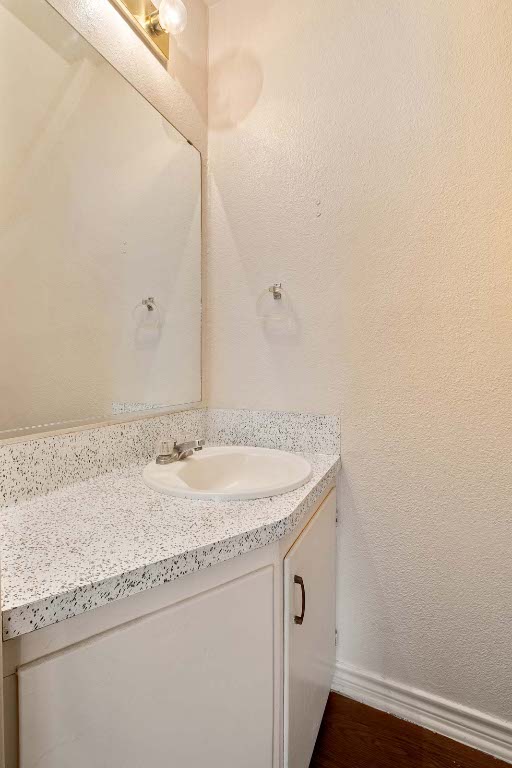 200 Concho Street, Unit B Lockhart, TX 78644 - Photo 7 of 13 Bathroom featuring vanity, a textured wall, and dark wood-type flooring