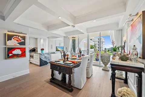 a view of a dining room and kitchen with furniture a chandelier and wooden floor