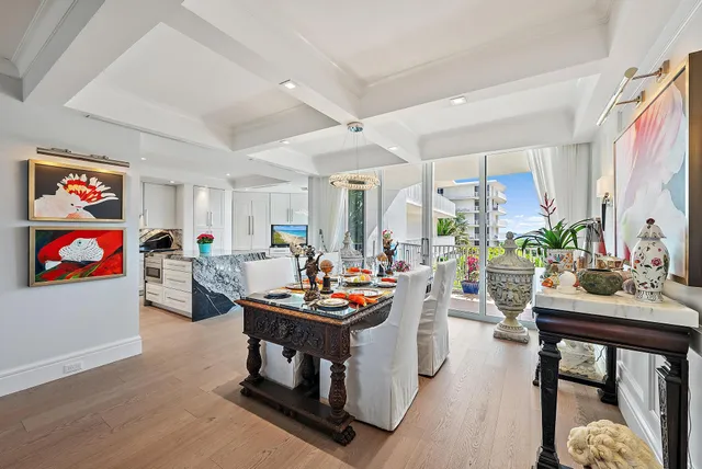 a view of a dining room and kitchen with furniture a chandelier and wooden floor