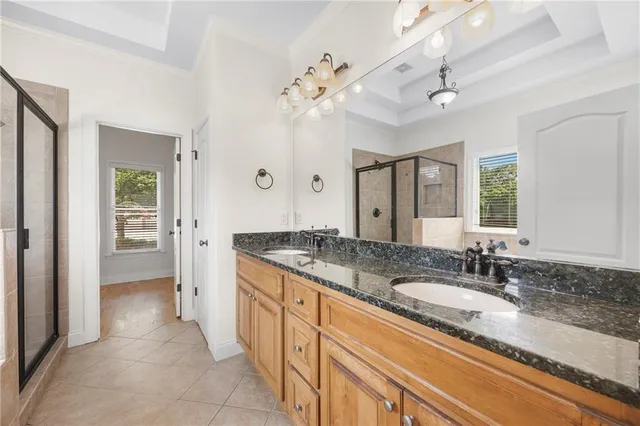 a spacious bathroom with a granite countertop sink a mirror and a shower