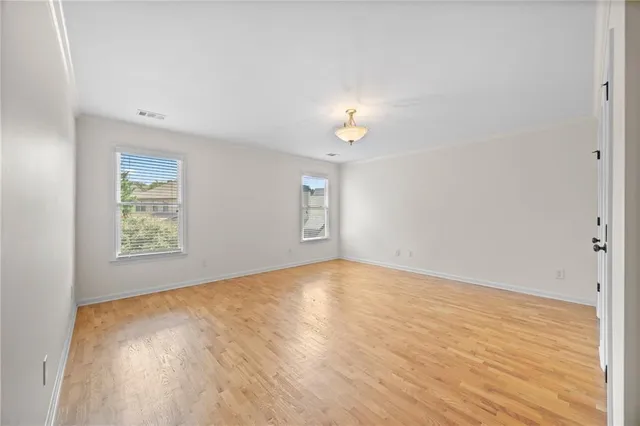 a view of an empty room with a window and wooden floor