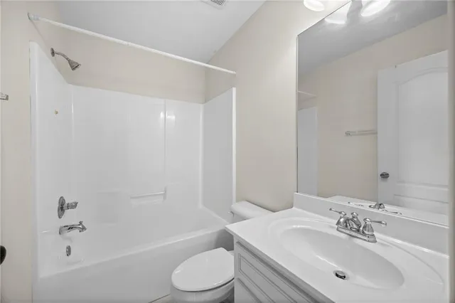 a bathroom with a bathtub shower sink mirror vanity and a toilet