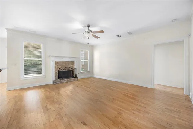 a view of empty room with fireplace and wooden floor