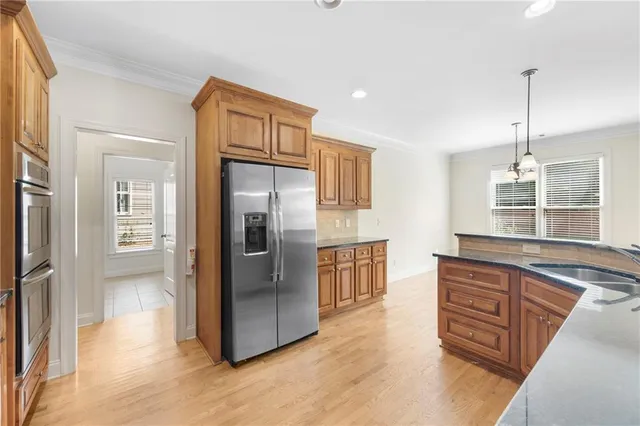 a kitchen with stainless steel appliances granite countertop a refrigerator a sink and wooden floors