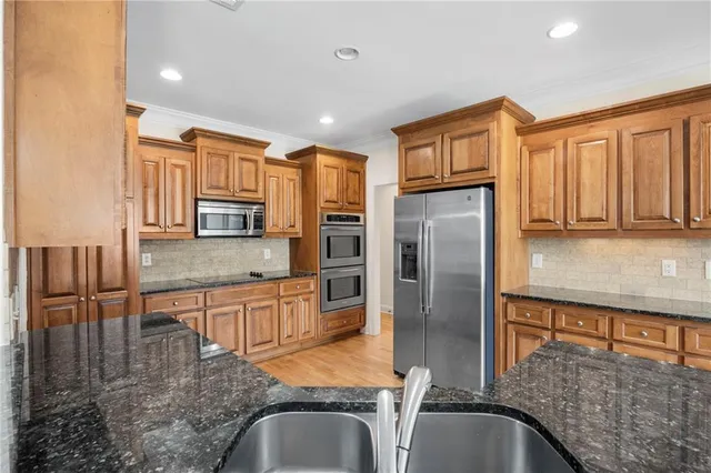 a kitchen with stainless steel appliances granite countertop a refrigerator a stove and white cabinets with wooden floor