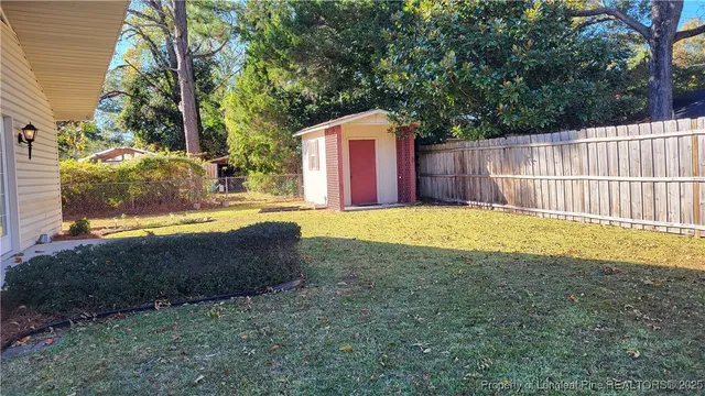 a view of backyard with tree and wooden fence