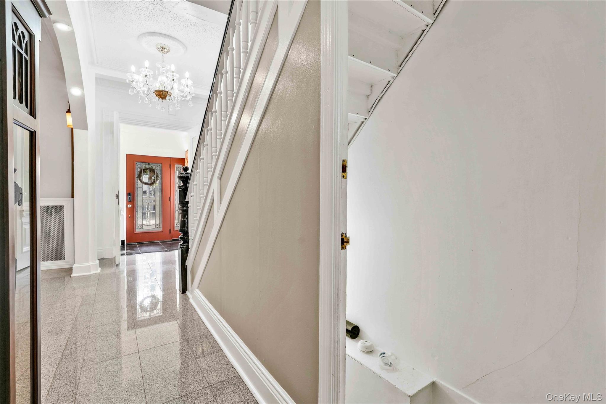 80-63 87th Road Queens, NY 11421 - Photo 24 of 50 Hallway featuring stairs, granite tiled floors, a chandelier, and crown molding