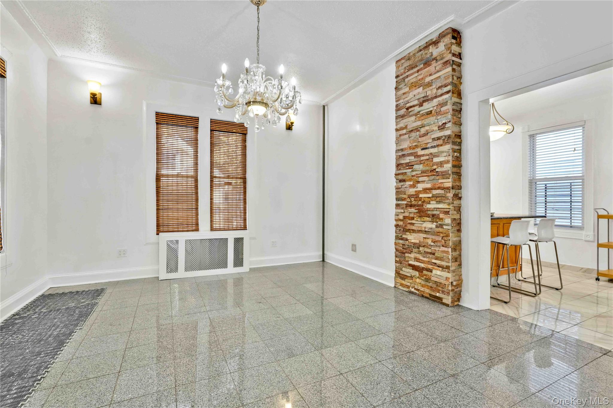 80-63 87th Road Queens, NY 11421 - Photo 25 of 50 main dining room featuring a chandelier, radiator heating unit, granite tiled floors, and crown molding