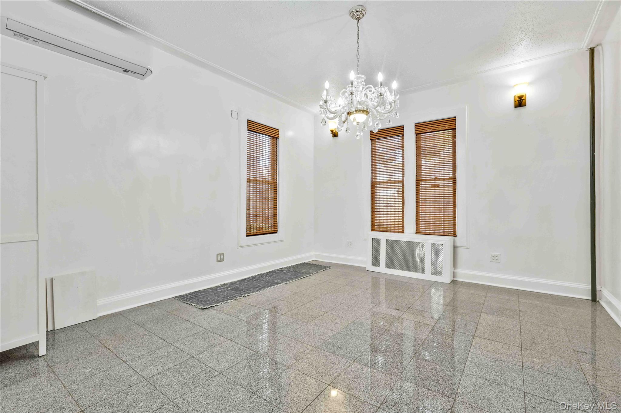 80-63 87th Road Queens, NY 11421 - Photo 26 of 50 living room with a wall unit AC, granite tiled floors, and a chandelier