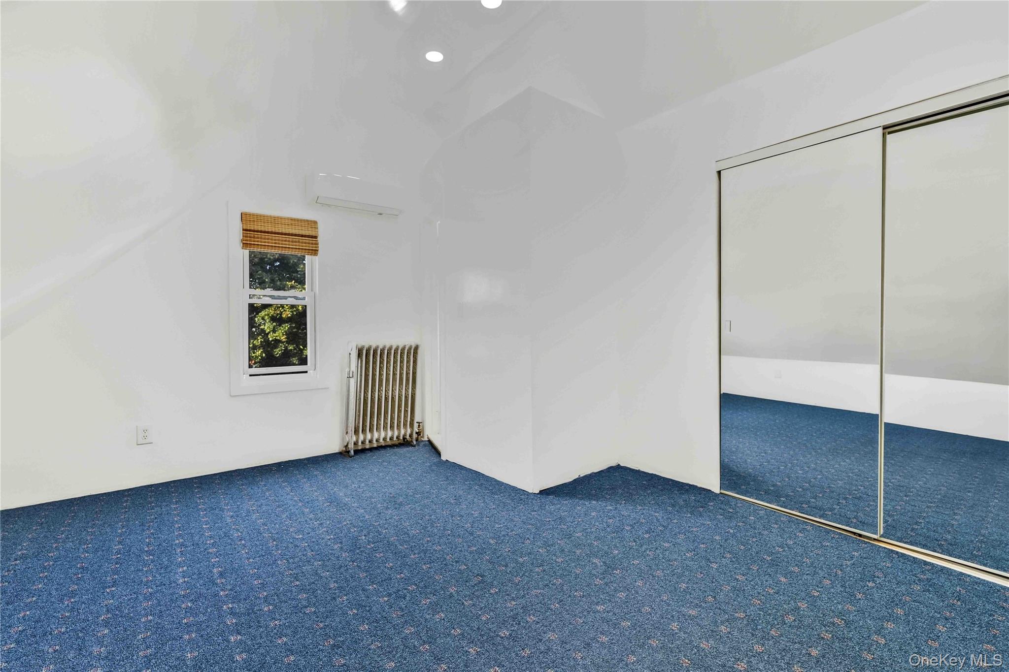 80-63 87th Road Queens, NY 11421 - Photo 49 of 50 Bonus bedroom with radiator, a wall mounted AC, carpet flooring, and vaulted ceiling